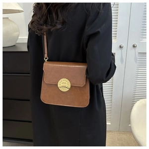 Close-up of retro crossbody bag with gold embossed lock worn on shoulder