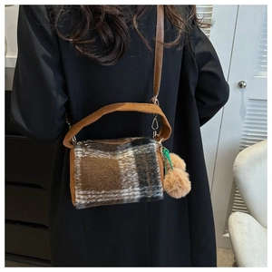 Detail of checkered plush crossbody bag with pom-pom charms and corduroy handle