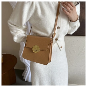 Detailed view of vintage brown crossbody bag with a round embossed metal lock