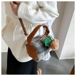 Detail of plush faux fur cylinder bag with brown corduroy handle and leaf pendant