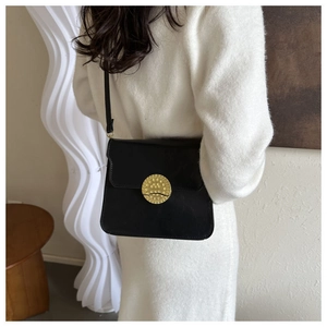 Detail of a black leather crossbody bag featuring a golden vintage embossed metal buckle