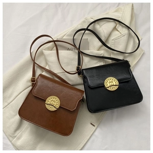 Detail of vintage square leather crossbody bags with textured gold circular buckle