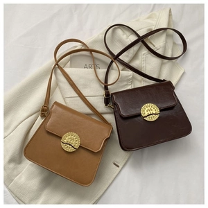 Detail view of vintage brown crossbody bags with round metal locks on textured blazer