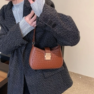 Detail view of brown woven shoulder bag featuring a gold rectangular metal lock closure