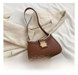 Close-up of brown woven baguette bag with a metallic square buckle on white fabric