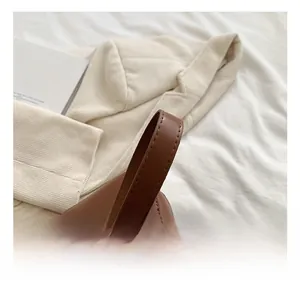 Detail view of deep brown leather shoulder bag handle with precise stitching on white fabric