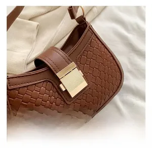 Detailed macro of the gold rectangular metal buckle on a brown woven texture handbag