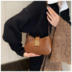 Close-up of the woven texture and gold buckle on a brown leather hobo shoulder bag