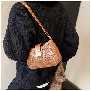 Brown woven shoulder bag with gold clasp shown on a model in a black knit sweater