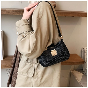Detail of black crocodile embossed shoulder bag featuring a sleek golden square buckle
