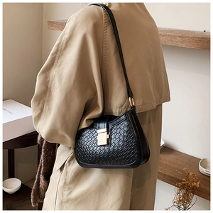 Detail of black crocodile texture shoulder bag with golden buckle and sleek leather finish