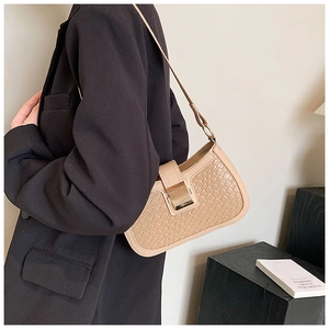 Detail of beige woven texture underarm bag featuring a vintage gold metal buckle