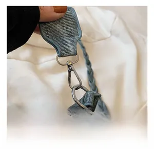 Detailed close-up of blue denim bag featuring silver metal swivel hook and braided strap