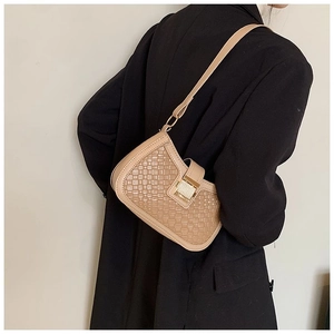 Detail of a beige woven underarm bag with gold buckle on a model in a black blazer