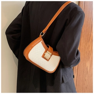 Detail of a brown leather and white woven shoulder bag on a black blazer jacket