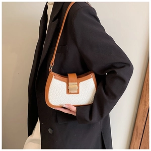 Detail of woven texture white shoulder bag with brown trim and gold square metal lock