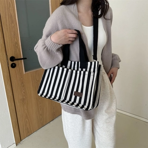 Large striped canvas tote bag with black handles and adjustable shoulder strap