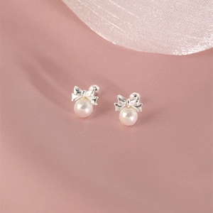 Elegant bow stud earrings with white pearls on pink silk fabric, French style jewelry