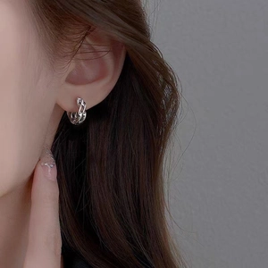 Detailed close-up of silver Mobius hoop earrings with a textured liquid metal finish