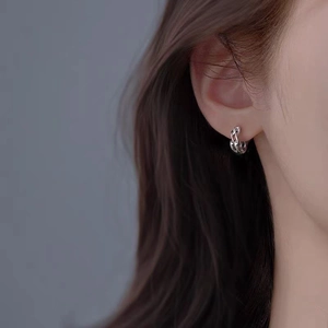 Close-up of silver Mobius hoop earrings with twisted rope texture on a model's ear