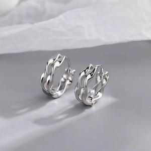 Macro detail of silver Mobius hoop earrings with polished wavy intersecting lines