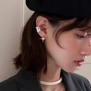 Boucles d'oreilles étoile argentées et large anneau sur modèle pour un look minimaliste
