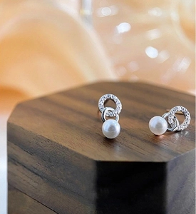 Macro view of French-style bow pearl earrings with s925 silver base and sparkling zircons