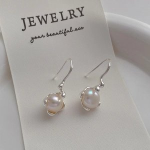 Close-up of elegant silver bow pearl drop earrings displayed on a jewelry card