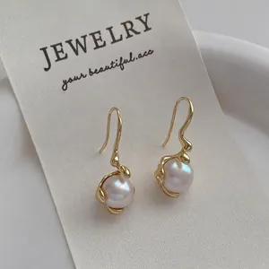 Macro view of gold bow pearl earrings with irregular textured metal on display