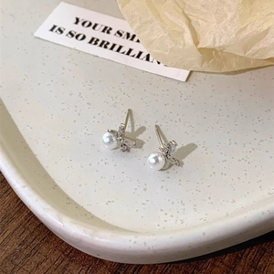 Detail of bowknot pearl earrings on a beige ceramic tray with elegant decor