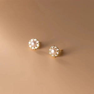 Detailed close-up of a sunflower-shaped pearl stud earring with sparkling gold plating