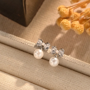 Elegant bow zircon and pearl stud earrings shown in a 45-degree angle professional view