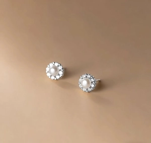 Macro detail of French style bow-tie pearl earrings with sparkling diamond halo