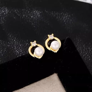 Macro shot of French luxury pearl stud earrings with gold frame and zircon detail