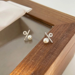 Macro shot of silver bow earrings with micro-zirconia inlays and a round white pearl