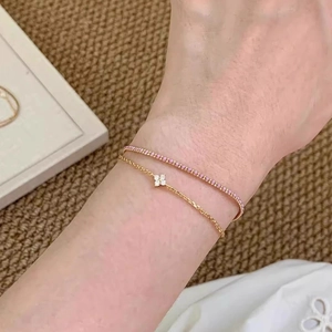 Double-layered gold bracelet featuring pink gemstone pavé chain and a four-petal flower charm