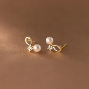 Elegant gold bow earrings with white pearls and sparkling cubic zirconia stones