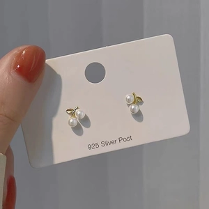 Detail of cherry stud earrings with white pearls, gold leaves, and 925 silver posts