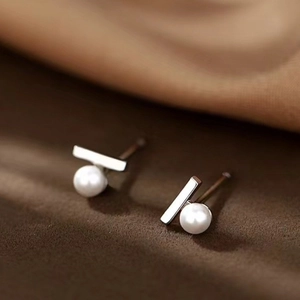 Close-up of minimalist silver bow earrings featuring round white pearls with soft luster
