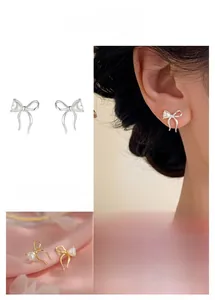 Detail of bow earrings with heart pearl in gold and silver finish on silk and model