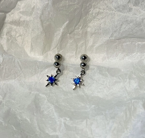 Détail de boucles d'oreilles étoiles avec pierre bleue sur fond de papier froissé
