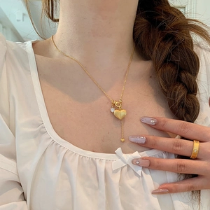 Golden heart necklace with matte texture and small diamond pendant worn by model