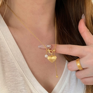 Elegant gold heart pendant necklace and crystal ring set on a female model