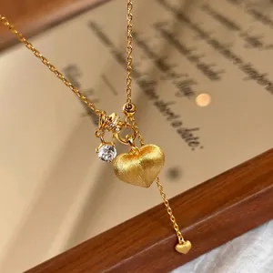 Vintage gold heart necklace with brushed metal pendant and zircon on a mirror
