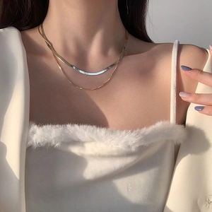 Detail of layered gold snake bone chain necklace on neck for minimalist french style