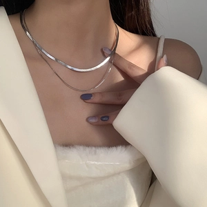Detail of layered silver snake chain necklace worn on model with elegant textures
