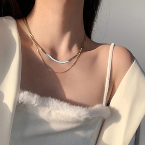 Detail of layered double gold snake bone chain necklace on female model neck