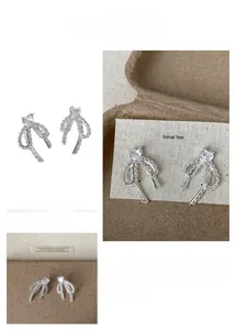 Détail de la boucle d'oreille nœud en dentelle avec zircon en forme de cœur argenté