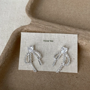Boucles d'oreilles nœud argenté avec zircon cœur sur carte de présentation