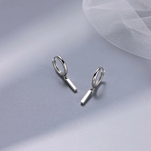 Close-up of polished gold bar drop hoop earrings on elegant mesh fabric background